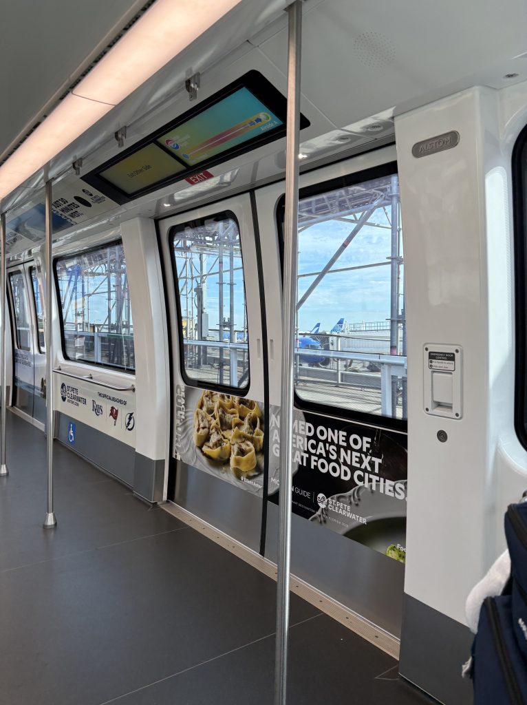 Jeannie and Skip traveling through Tampa International Airport on the automated people mover before their flight to Los Angeles.